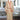 A salmon pink and olive green floral print robe with contrasting trim displayed on a mannequin in a room with furniture and decorative items in the background.